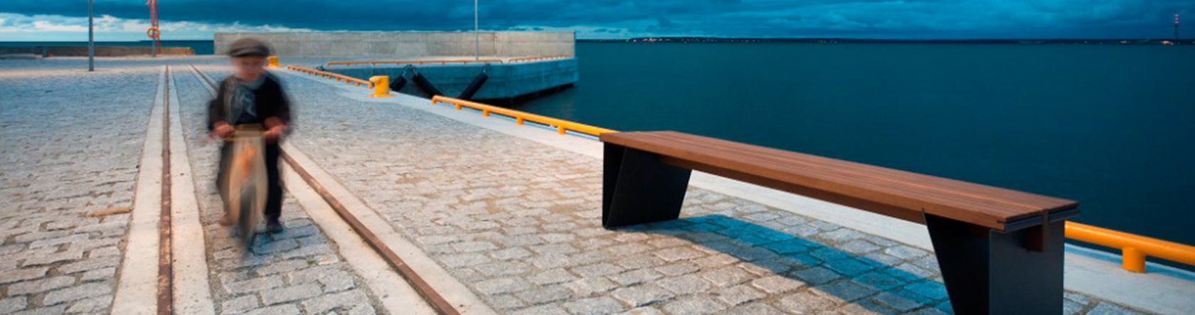 Kind auf einem Holzfahrrad vor einer stillvollen Parkbank.